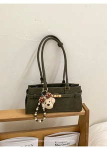 Détail du sac à bandoulière en daim vert foncé avec fermoir doré et breloque chien peluche
