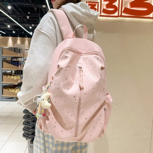 Detail of pink nylon backpack with silver stars print, front zipper, and rainbow charm