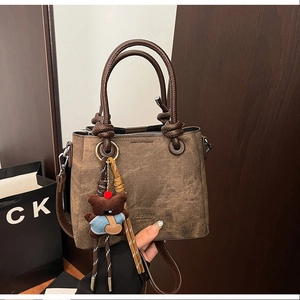 Detail of vintage brown textured bucket bag with decorative bear pendant and sturdy handles