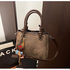 Macro detail of retro brown bucket bag featuring embossed text and cute bear charm