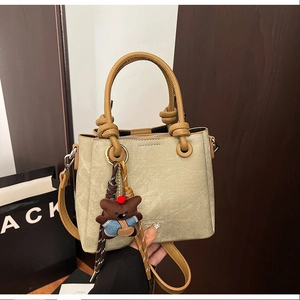 Detail of canvas bucket bag with leather handles and fashion logo with bear charm