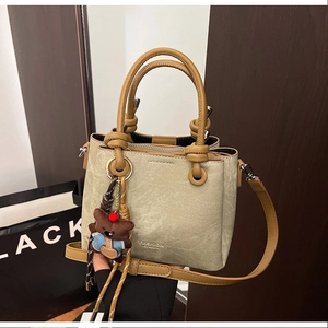 Detail of khaki bucket bag with FASHION logo, round handle and cute bear charm