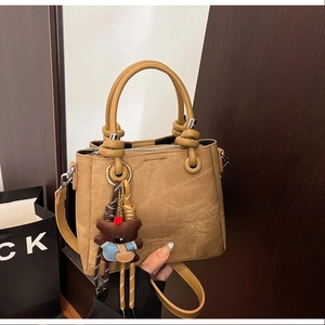 Close-up of brown bucket bag with FASHION embossment and cute bear charm detail