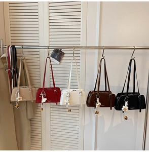 Detailed view of fashionable tote bags in five colors with floral charms on a rack