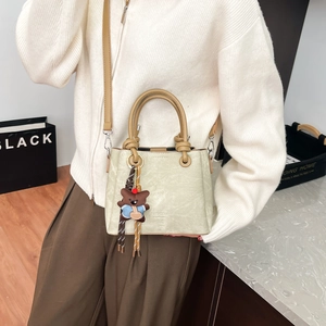 Detail of retro bucket bag with brown leather straps and cute plush bear charm decoration