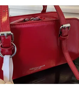 Detail of red patent leather tote bag showing silver metal hardware and double zipper