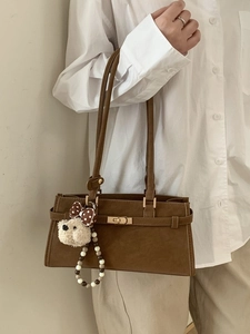 Sac sous le bras vintage marron avec fermoir doré et breloque ours sur modèle