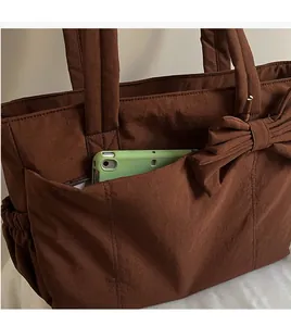 Detail of coffee brown tote bag with side pocket holding a green tablet for storage