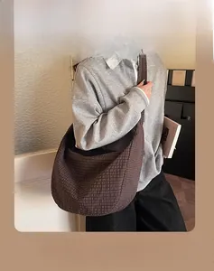 Detail of a large brown checkered dumpling crossbody bag showing textured fabric and spacious design