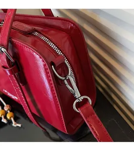 Close-up of bright red leather bag showing glossy texture and silver metal zipper detail