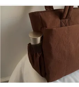Detail of coffee tote bag featuring side drawstring pocket with a silver water bottle
