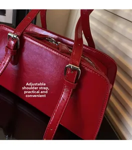 Detail view of red glossy leather shoulder bag with adjustable buckle strap and silver zipper