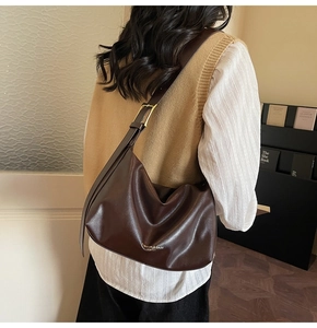 Détail du sac cabas marron foncé avec texture cuir, logo mode et boucle dorée