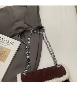 Close-up of quilted dark brown chain bag with white shearling trim and silver hardware