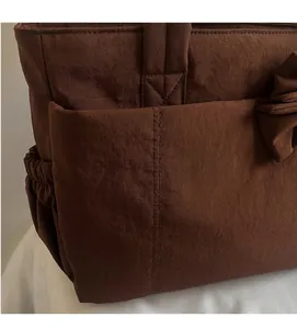 Detail of dark brown tote bag showing crinkled texture fabric and side pocket detail