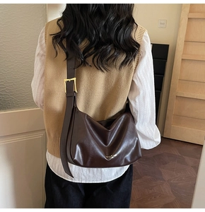 Detail of large brown tote bag with wide strap and golden buckle for daily commute