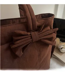 Detailed texture of a brown tote bag featuring a large decorative bow and wide handle