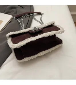 Detail of brown suede crossbody bag with white fleece trim and silver chain strap