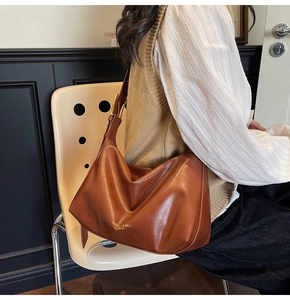 Detail of caramel brown leather tote bag with gold lettering and adjustable wide strap