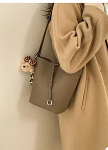 Dettaglio della borsa a secchiello in pelle marrone con un ciondolo a forma di orso