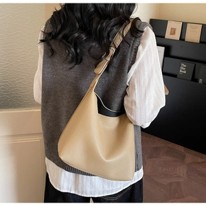 Detail showing the beige lychee grain leather texture and adjustable strap of hobo bag