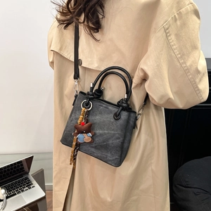 Detail view of vintage dark grey bucket bag with metal ring handle and plush bear charm