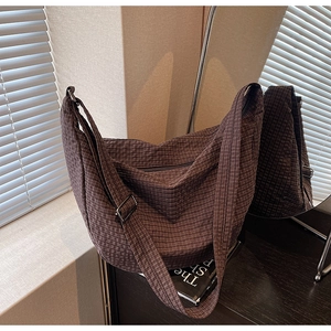 Detail of adjustable strap and silver metal buckle on brown checkered hobo bag