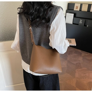 Detail view of brown lychee grain leather bucket bag with adjustable strap on a model
