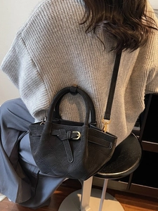 Zwarte gewatteerde draagtas met decoratieve gesp als crossbodytas op een model
