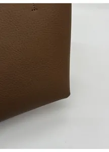 Macro shot of dark brown lychee grain leather texture and detailed stitching on bucket bag