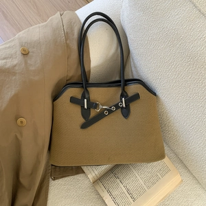Close-up of retro brown textured tote bag with black leather trim and silver metal buckle