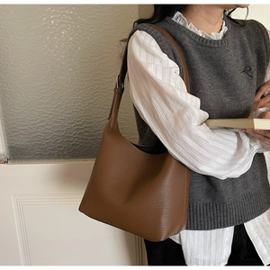 Detailed view of brown litchi grain leather hobo bag with adjustable strap on shoulder