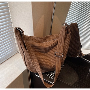 Macro detail of brown checkered hobo bag featuring adjustable metal buckle strap
