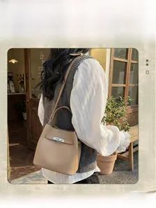 Detail of camel leather bucket bag with silver twist lock on stylish white shirt