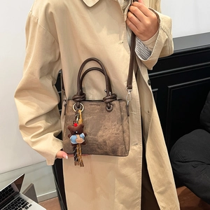 Retro brown bucket bag with embossed Fashion logo and cute bear charm shown on model