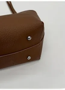 Detail of widened base with silver anti-wear metal studs on brown leather bag
