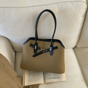 Detail of vintage patchwork handbag with khaki canvas and black leather strap on a sofa