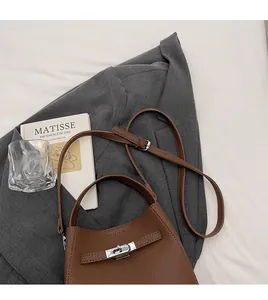 Detail of brown litchi pattern leather bucket bag with silver lock and adjustable strap
