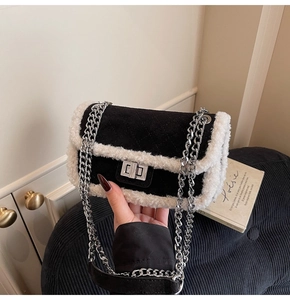 Detail of black quilted suede crossbody bag with white faux fur trim and silver chain