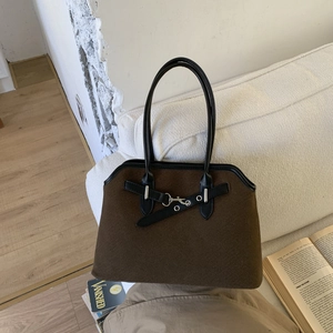 Deep brown felt tote bag with black handles on a sofa in a bright home setting