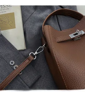 Detail of dark brown lychee leather handbag with silver metal twist lock and stitching