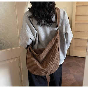Detail of a large brown plaid tote bag featuring a wide strap and minimalist style