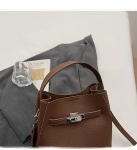 Detail of brown lychee grain leather bucket bag featuring a silver twist lock closure