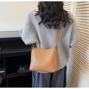 Detailed texture of caramel litchi grain leather on a stylish bucket shoulder bag