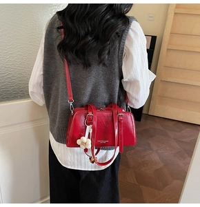 Chic red patent leather boston bag styled with a floral charm on a casual outfit