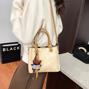 Detail of beige textured bucket bag with bear charm and Fashion Concept logo imprint