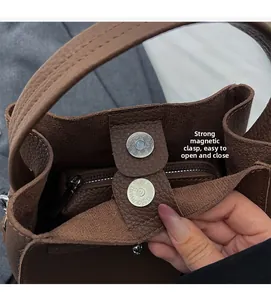Detail view of strong magnetic snap closures and leather texture on brown handbag