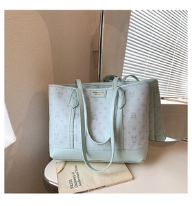 Detail of mint green tote bag featuring rabbit print and premium metallic brand logo