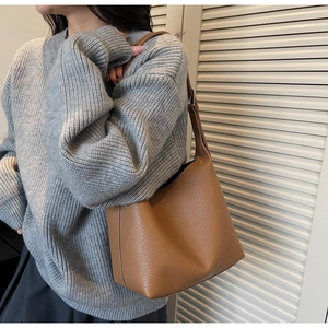 Detail showing caramel brown litchi pattern leather texture of the bucket shoulder bag
