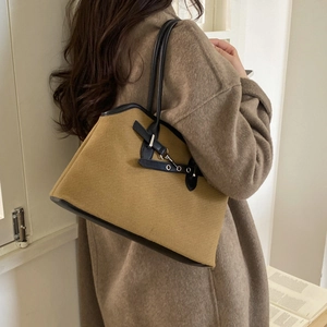 Detailed view of camel canvas tote bag with black leather straps and metal buckle
